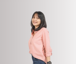 Seseorang berdiri menyamping dengan tangan berada di belakang, mengenakan jaket hoodie merah muda dan celana jeans; latar belakang gradasi abu-abu polos, wajah diburamkan.
